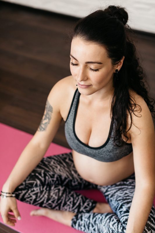Pregnant young woman doing breathing and relaxation exercises