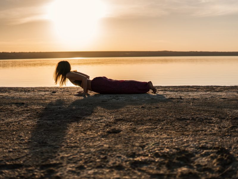Silhouette yoga woman on the beach at sunset. Silhouette woman on the beach at sunset doing yoga asana. Morning natural stretch warm-up training