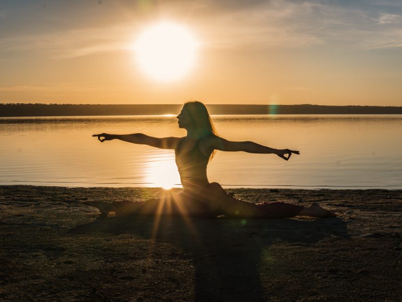 Silhouette yoga woman on the beach at sunset. Silhouette woman on the beach at sunset doing yoga asana. Morning natural stretch warm-up training